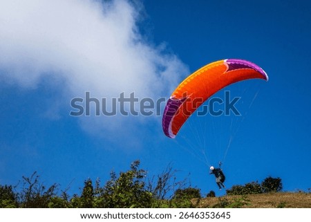 Para glider soaring gracefully in vivid skies above a lush natural landscape, capturing adventure, freedom, and outdoor activity.