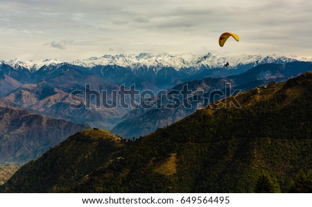 Para Gliding adventure at beautiful valley of Khajjiar near Dalhousie and Kalapathar, Himachal Pradesh, India. Himalayan Mountains in the background.