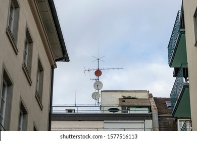 Parabolic Mirror And TV Antenna On A House Roof