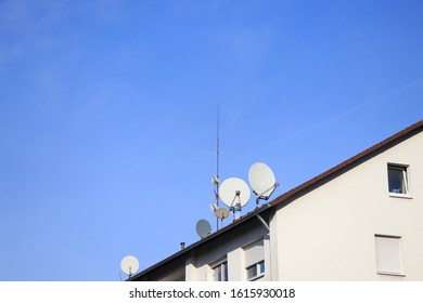 Parabolic Mirror And TV Antenna On A House Roof