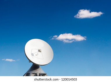 A Parabolic Reflector Antenna Is Isolated Against A Blue Background With White Clouds