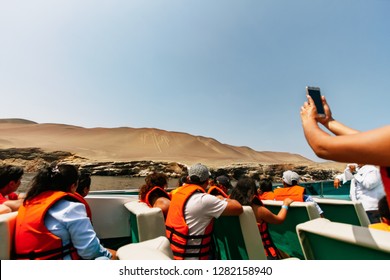 Paracas, Peru - February 15, 2018: Tourist Woman Takes A Photograph With Her Cell Phone From The Candelabra Geoglyph From A Boat While Traveling To The Ballestas Islands