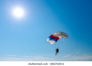 Parachutist is flying slowly down with an open parachute. Skydiving, gliding, parachute jump