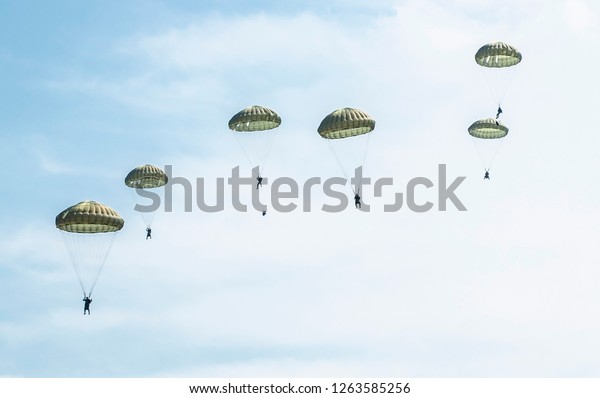 Parachutists jump\
from a military plane during a military exercise. Many soldiers\
with parachutes in the\
sky.