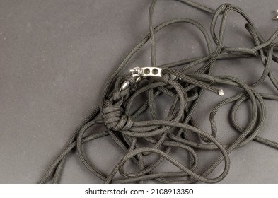 Paracord with braided clasp and rigging strap lying chaotically. A black rope against a black background. Close-up. Selective focus. - Shutterstock ID 2108913350