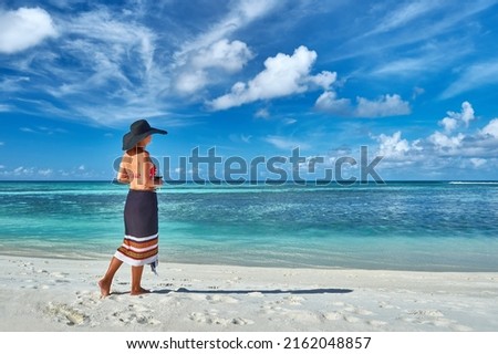 Paradise beaches of the Maldives. Tourism, travel and vacation in a luxury resort. Woman in bikini relaxing on the beach