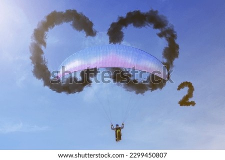 Paraglider in the blue sky on a sunny day. Blue sky with word CO2 . Global warming concept. Natural disasters and cataclysms
