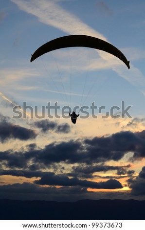 Paraglider in the cloudy sunset sky