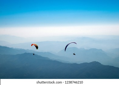 Paraglider flies in the Himalayan mountains. Paragliding in the sky. Mans against the blue sky. Bright athletes fly in the sky. Extreme sport. State in the northern part of India. - Shutterstock ID 1238746210