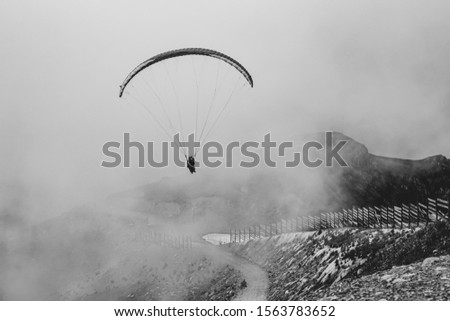 paraglider flies in the mountains against the clouds