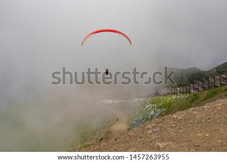 paraglider flying from the mountain in the fog