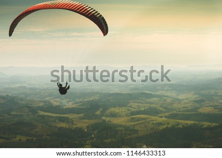 Paraglider flying on the beautiful sunny sky over the green mountains in Poços de Caldas, Minas Gerais, Brazil, June 2018