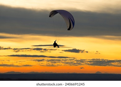Paraglider silhouette against sunset Paragliding on Pálava hill in Czech Republic. 