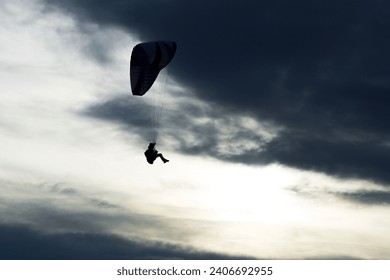 Paraglider silhouette close up against clouds. Paragliding on Pálava hill in Czech Republic.