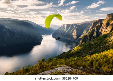 Paraglider silhouette flying over Aurlandfjord, Norway.