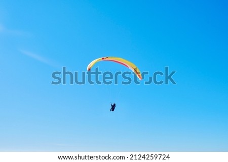 Paraglider soaring against the backdrop of a sunny blue sky. Bottom view