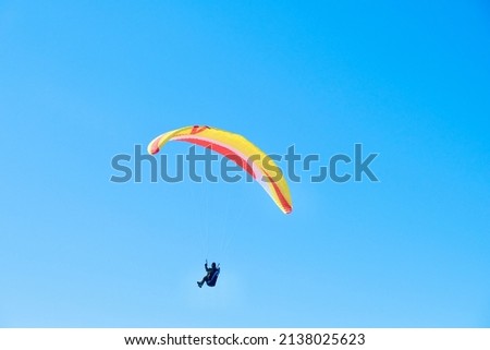 Paraglider soaring against the backdrop of a sunny blue sky. Bottom view