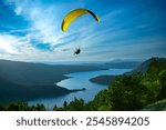 Paraglider with Yellow Canopy Soaring Over Lake Annecy on a Sunny Summer Day - Thrilling Active Sport Adventure