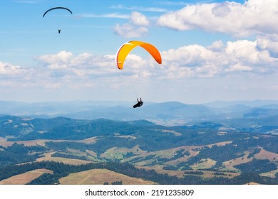 Paragliding Above The Mountain Valley. Extreme Outdoor Sports. Adventure And Travel Concept. Clouds On The Sky In Summer