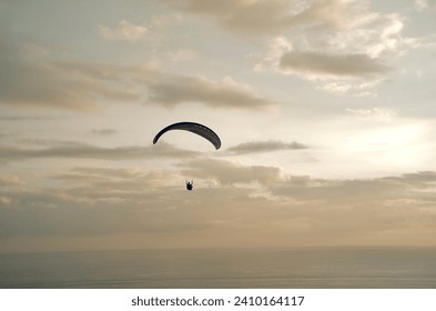 Paragliding concept, paraglider pilot flying in the evening sky on the beautiful background of the sky and sea south of Java Island, horizontal photo - Powered by Shutterstock