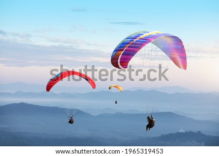 Paragliding in the sky. Paraglider  flying over Landscape sun set Concept of extreme sport, taking adventure challenge. 
