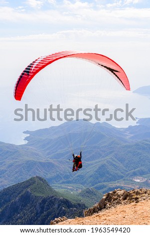 Paragliding in sky. Paraglider tandem flying over the sea and mountains. Extreme sport