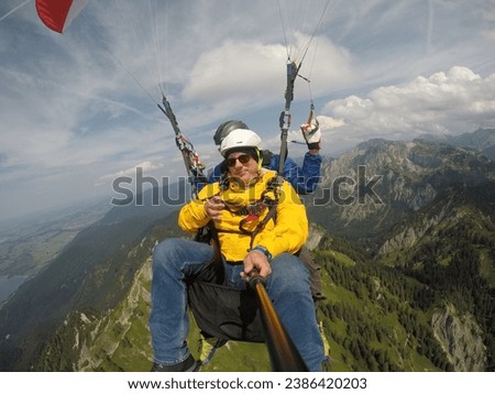 Paragliding In Tandem. People In The Sky. Two Men Flying Over The Mountains. Schwangau, Bavaria, Germany