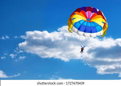 Paragliding using a parachute on the background of cloudy blue sky.
