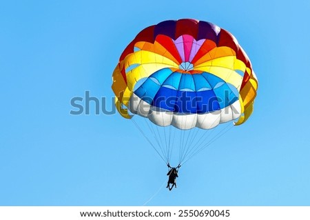 Paragliding using a parachute on background of blue sky.