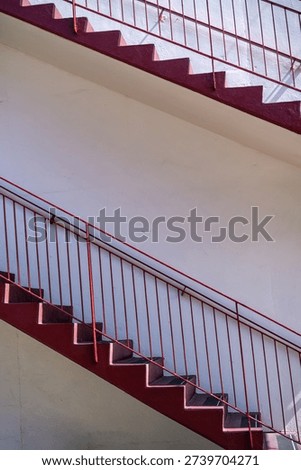 Parallel Red Staircases and Railing on a White Building