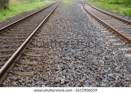 Parallel train tracks disappearing into the distance on a cloudy day, symbolizing travel, journey, and transportation