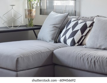 Parallelogram pattern pillow and gray pillows setting on gray sofa at comfortable living corner