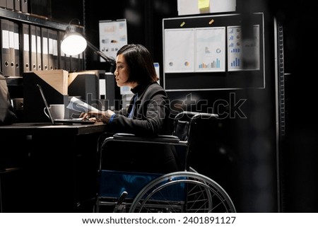 Paralyzed businesswoman employee in wheelchair checking bookkeeping analytical data documents. Accountant with disability in business company file cabinet depository filled with charts and folders