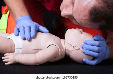 Paramedic demonstrating life function check on infant dummy - Powered by Shutterstock