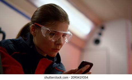 Paramedic Doctor Using Mobile Phone In Emergency Vehicle. Portrait Ambulance Assistant Looking On Smartphone Screen. Closeup Medical Technician Holding Cellphone In Hands. Face Protective Glasses 