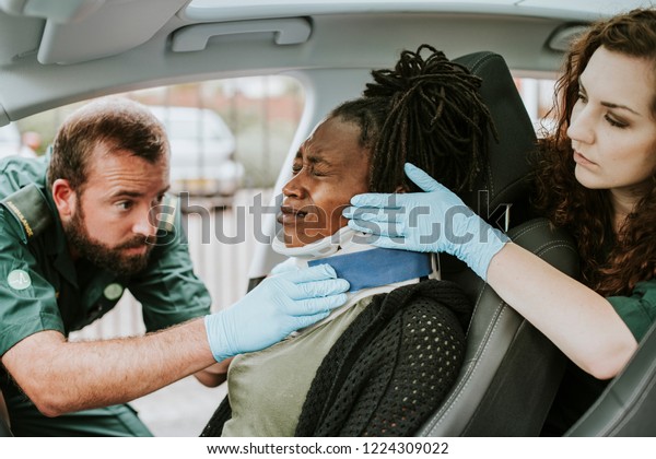 Paramedic placing a cervical collar to an\
injured woman from car\
accident