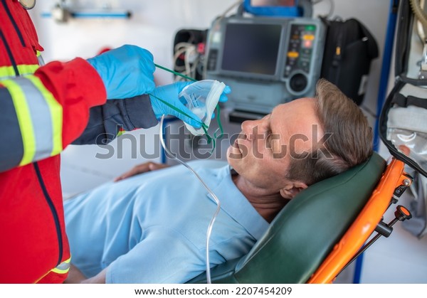 Paramedic\
preparing an unconscious man for oxygen\
therapy