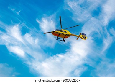 Paramedic Rescue Helicopter Against Blue Cloud Sky. Starting Helicopter, Flying Ambulances, Air Ambulance In Germany. German Text Notarzt - Emergency Doctor. View From Below