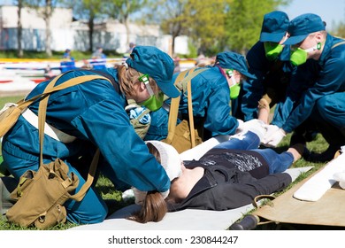 Paramedic Succor A Woman Patient With Protective Gas Mask, Brain Injury And Broken Leg