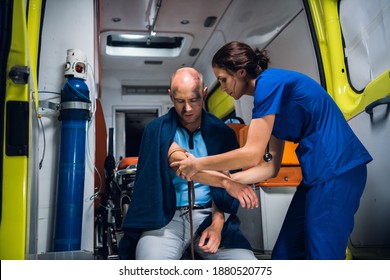 Paramedic wraps a tourniquet around the hand of an injured man in an ambulance car.