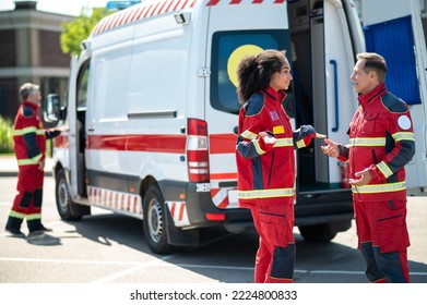 Paramedical Personnel Standing Near The EMS Vehicle During The Conversation