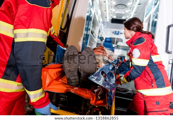 Paramedics transporting patient on gurney in\
ambulance car