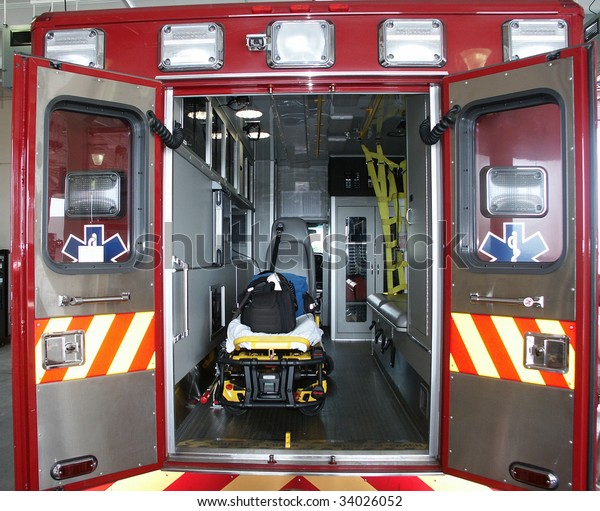 Paramedic\'s truck with open back doors, where\
stretcher and medical equipment is visible. All trademarks, names\
and identifications\
removed.