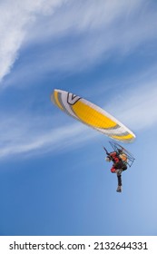 Paramotor flying in a blue sky. Adventuring with paramotor in the sky with beautiful yellow wing.
