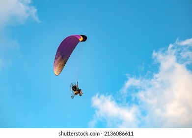 Paramotor Flying through sunlight with Blue Sky.Adventure man active extreme sport pilot flying in sky with paramotor engine glider parachute.