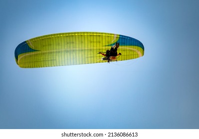 Paramotor Flying through sunlight with Blue Sky.Adventure man active extreme sport pilot flying in sky with paramotor engine glider parachute.