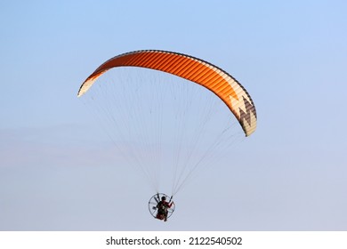Paramotor pilot flying in a blue sky	