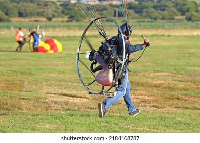 Paramotor pilot taking off from a field