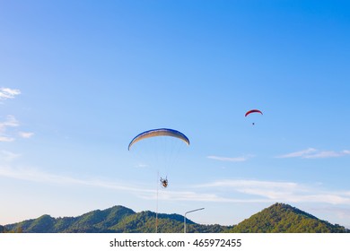 Paramotor wing flying on blue sky, soft focus.