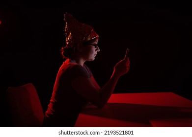 Paranoid Caucasian Woman Using Smartphone Wearing Tinfoil Hat. Conspiracy Theory. 